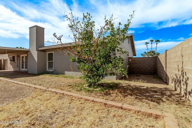 rear view of property with a patio, french doors, a fenced backyard, and a chimney