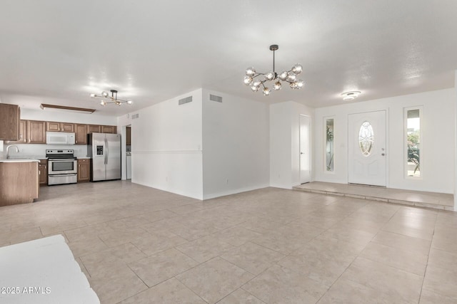 unfurnished living room featuring visible vents, a notable chandelier, and light tile patterned flooring