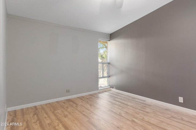 spare room with light hardwood / wood-style floors and lofted ceiling