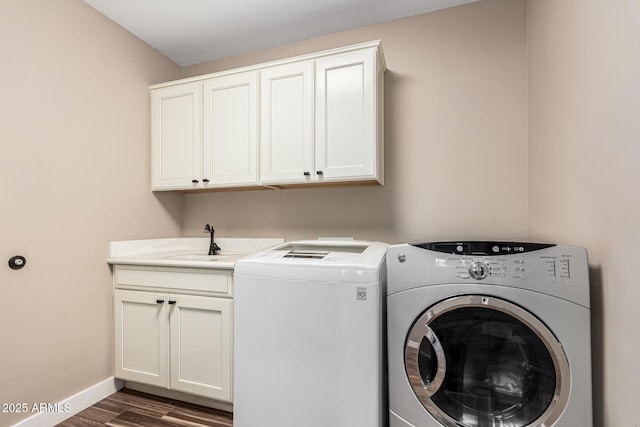 laundry room featuring sink, dark hardwood / wood-style flooring, independent washer and dryer, and cabinets