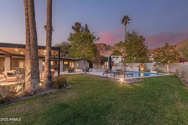 yard at dusk with a patio and a fenced in pool