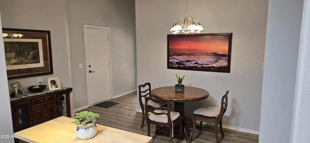 dining area featuring dark wood-type flooring, baseboards, and an inviting chandelier