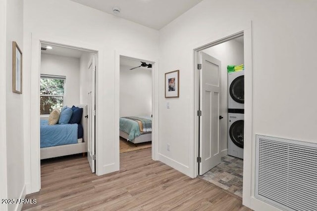 interior space with stacked washer and clothes dryer and light hardwood / wood-style flooring