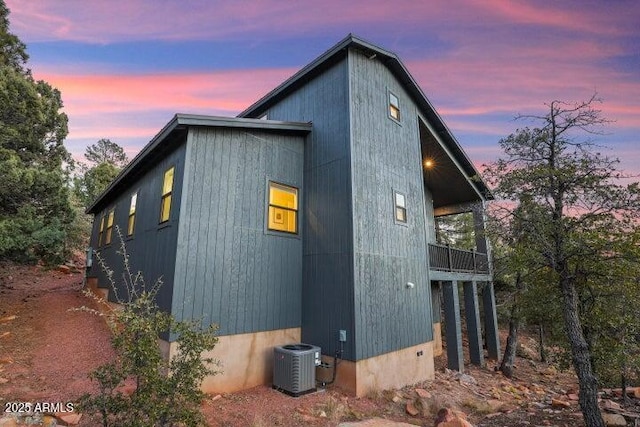 property exterior at dusk featuring a balcony and central air condition unit