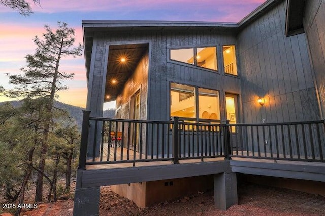 back house at dusk featuring a wooden deck