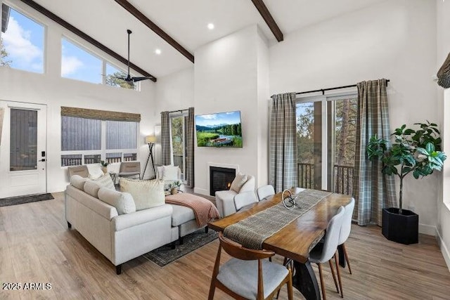 living room with high vaulted ceiling, beam ceiling, and light hardwood / wood-style flooring