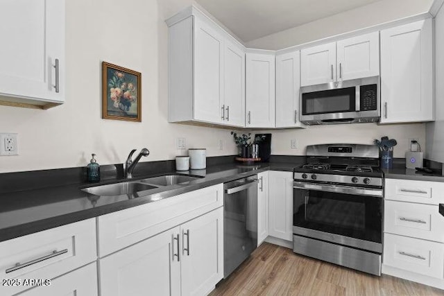 kitchen featuring stainless steel appliances, sink, white cabinets, and light hardwood / wood-style floors