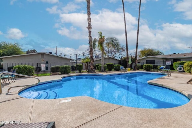 pool with a patio area and fence