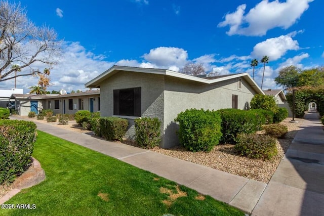 view of home's exterior featuring stucco siding and a lawn