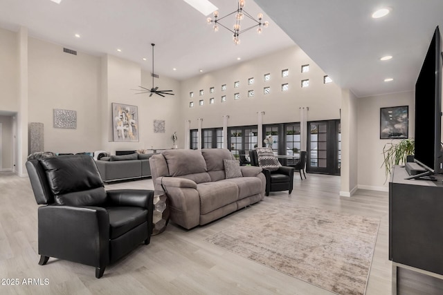 living room with recessed lighting, visible vents, a towering ceiling, light wood-style floors, and baseboards