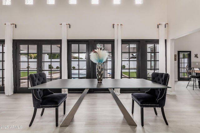 dining room featuring french doors, a high ceiling, and light wood-style floors