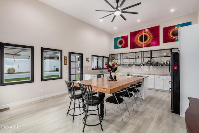 dining room with recessed lighting, a towering ceiling, visible vents, baseboards, and light wood finished floors