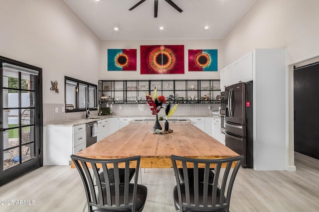 kitchen with tasteful backsplash, light countertops, fridge with ice dispenser, and a high ceiling