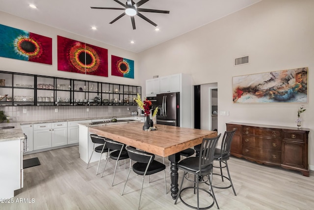 kitchen featuring white cabinets, light wood-style floors, visible vents, and black refrigerator with ice dispenser