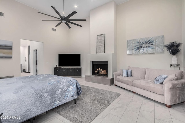 bedroom with recessed lighting, visible vents, a towering ceiling, marble finish floor, and a tiled fireplace