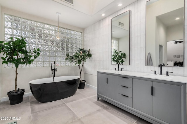 full bathroom featuring double vanity, a soaking tub, visible vents, and a sink