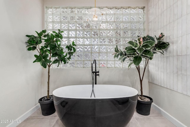 full bathroom with tile patterned flooring, a freestanding tub, tile walls, and baseboards