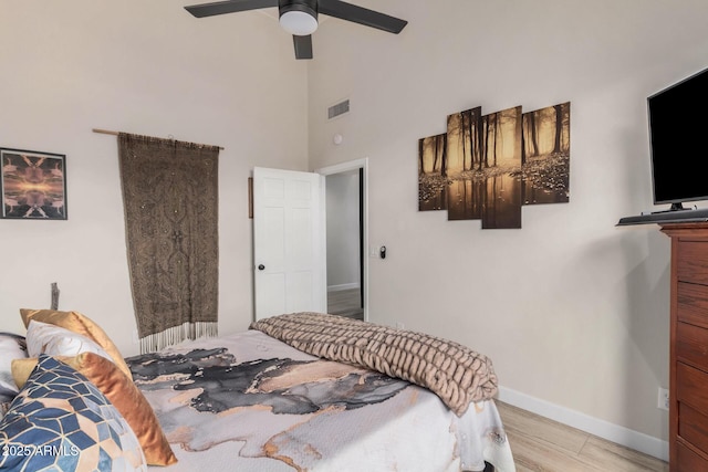 bedroom featuring visible vents, a ceiling fan, wood finished floors, high vaulted ceiling, and baseboards