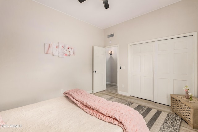 bedroom with light wood finished floors, visible vents, baseboards, a ceiling fan, and a closet