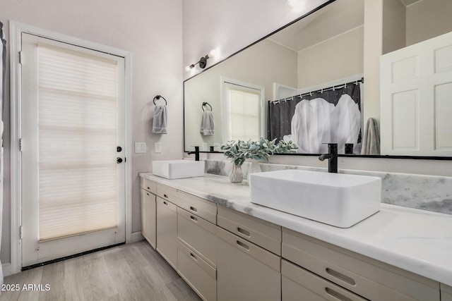 full bathroom with double vanity, a sink, and wood finished floors