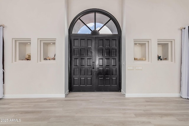 entrance foyer featuring wood finished floors, a towering ceiling, and baseboards