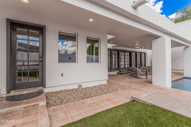 property entrance with stucco siding, an outdoor hangout area, and a patio