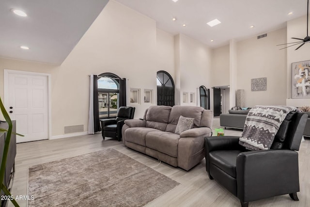 living room featuring high vaulted ceiling, visible vents, light wood-style floors, and a ceiling fan