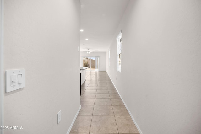 hall featuring recessed lighting, light tile patterned flooring, and baseboards