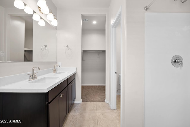 bathroom with double vanity, tile patterned flooring, a spacious closet, and a sink