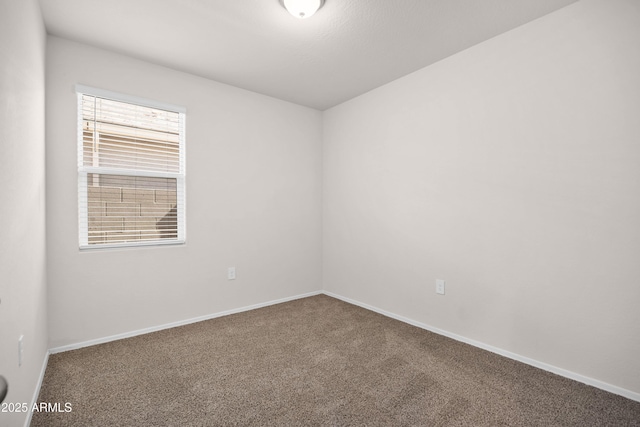 carpeted spare room featuring baseboards