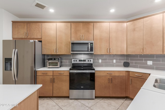 kitchen featuring light tile patterned floors, appliances with stainless steel finishes, and decorative backsplash