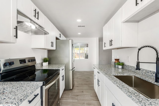 kitchen with electric range, sink, light stone counters, white cabinets, and light wood-type flooring