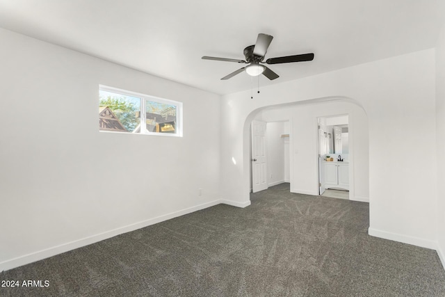 empty room with ceiling fan and dark carpet