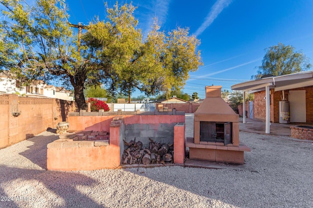 view of yard with a patio, an outdoor fireplace, and water heater