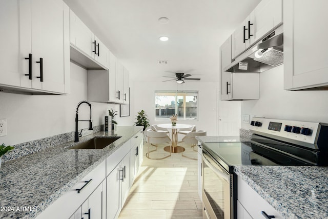 kitchen with stainless steel electric stove, sink, ceiling fan, light stone countertops, and white cabinetry