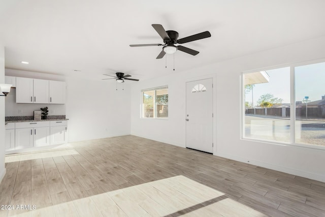 unfurnished living room with light hardwood / wood-style flooring and ceiling fan