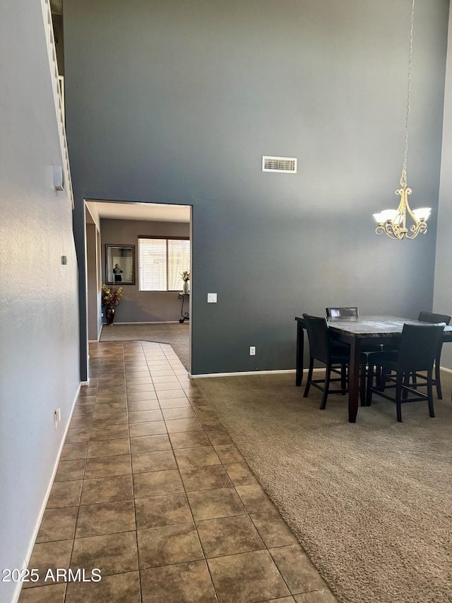 9108 W Kirby Ave, Tolleson, AZ 85353 - carpeted dining room featuring tile patterned flooring, visible vents, a high ceiling, baseboards, and a notable chandelier