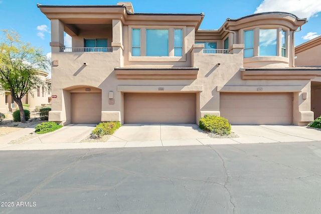 view of front of home featuring a garage, a balcony, and stucco siding