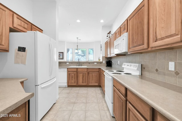 kitchen featuring white appliances, tasteful backsplash, light countertops, and a sink