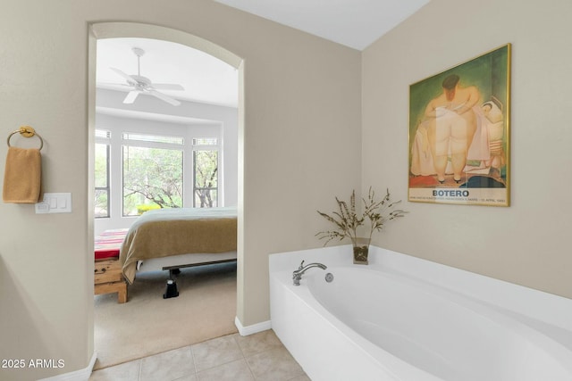 bathroom with ensuite bathroom, a ceiling fan, baseboards, a bath, and tile patterned floors