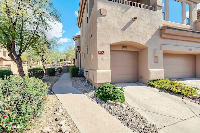 exterior space with concrete driveway, an attached garage, and stucco siding