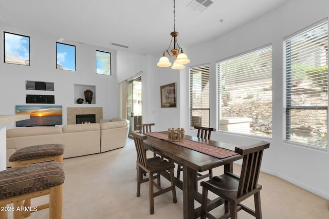 dining area with light carpet, a lit fireplace, and visible vents