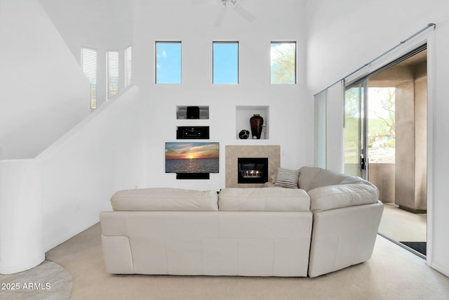 living area with ceiling fan, carpet floors, a high ceiling, and a high end fireplace