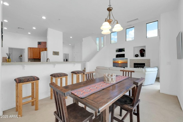 dining room featuring a fireplace, visible vents, and light colored carpet