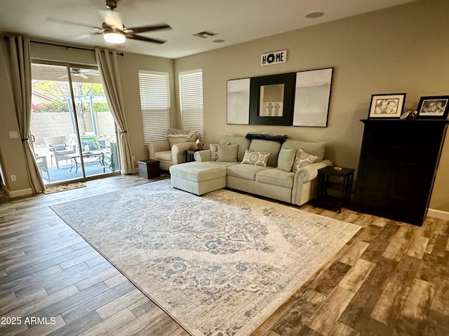 living area with visible vents, baseboards, a ceiling fan, and wood finished floors