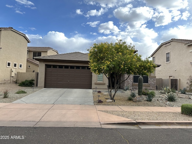 view of front of home with an attached garage, driveway, stucco siding, and fence