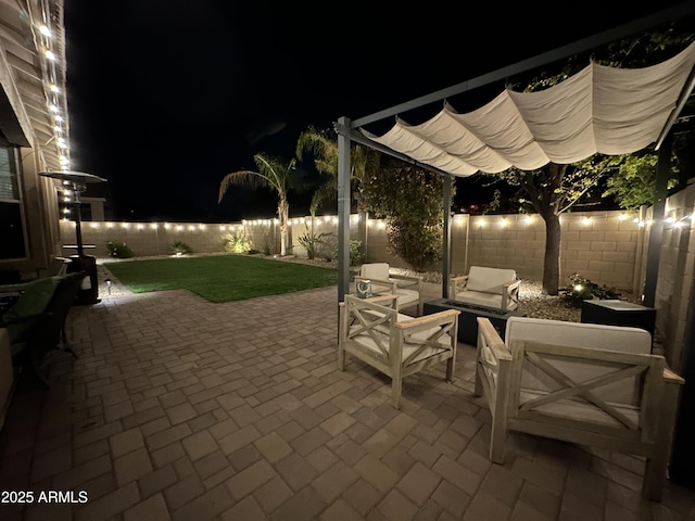 patio at night with a fenced backyard and a lawn