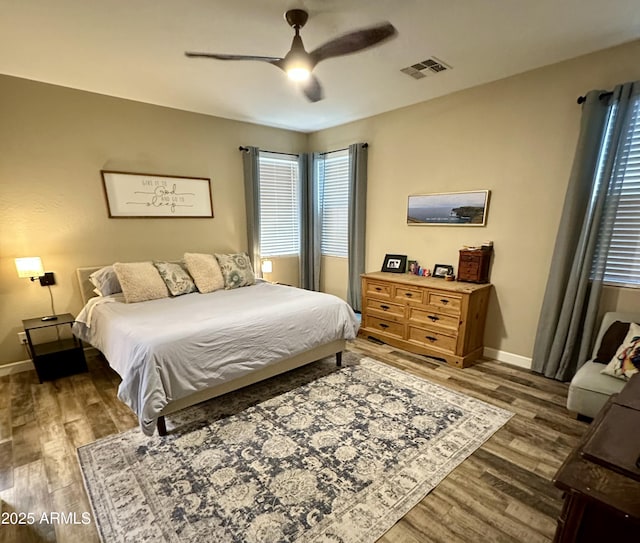 bedroom with visible vents, baseboards, ceiling fan, and wood finished floors