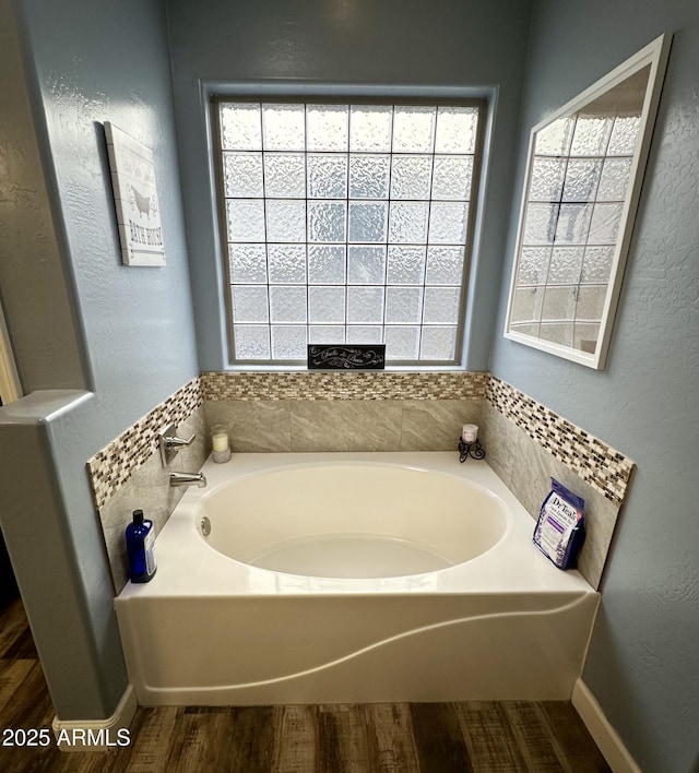 bathroom with a bath, plenty of natural light, and wood finished floors