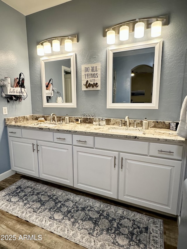 bathroom with double vanity, a sink, and a textured wall
